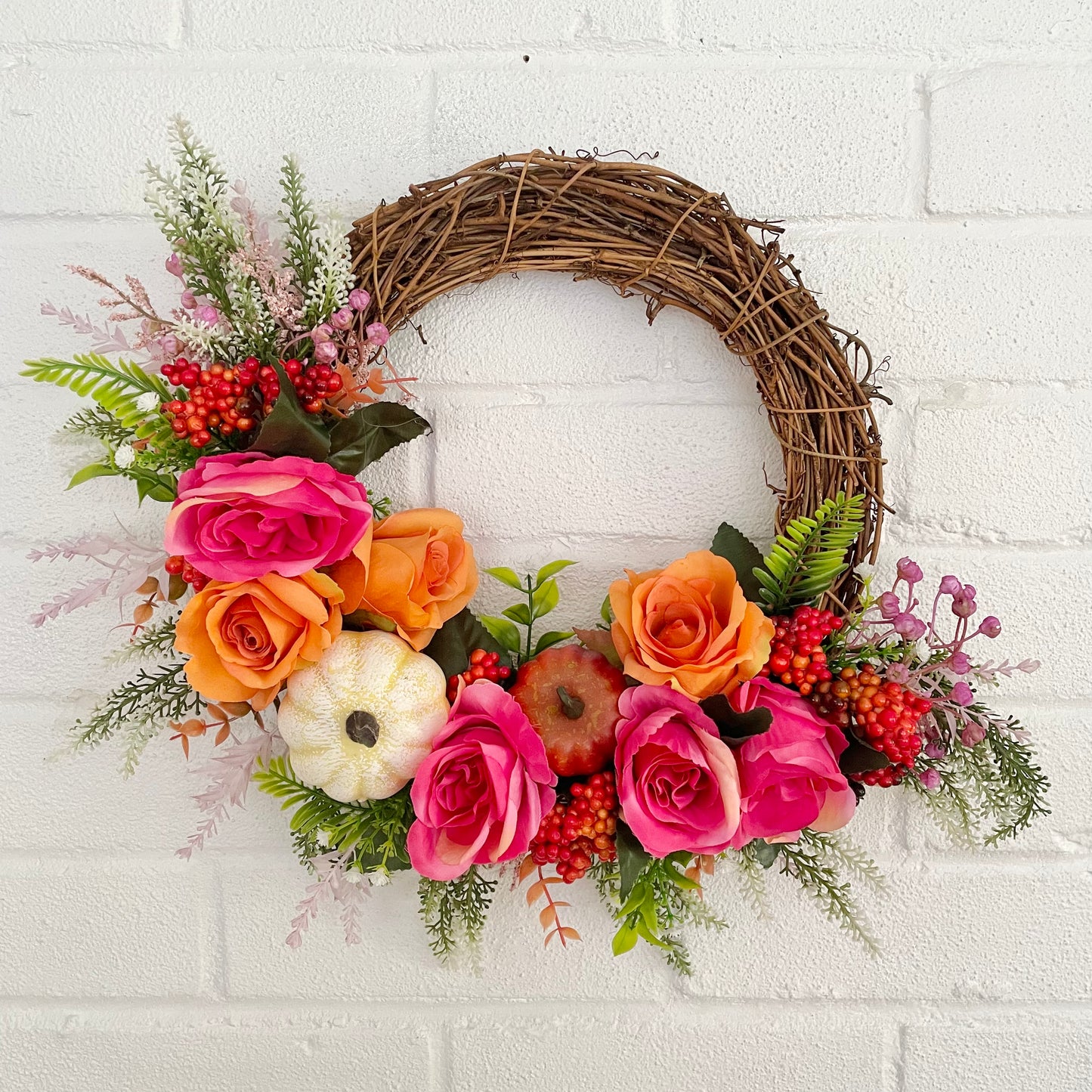 Autumn flower door wreath with pink and orange roses and pumpkins 