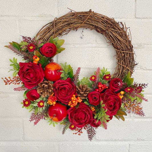 Autumn flower door wreath with red roses, apples, daisies and pine cones