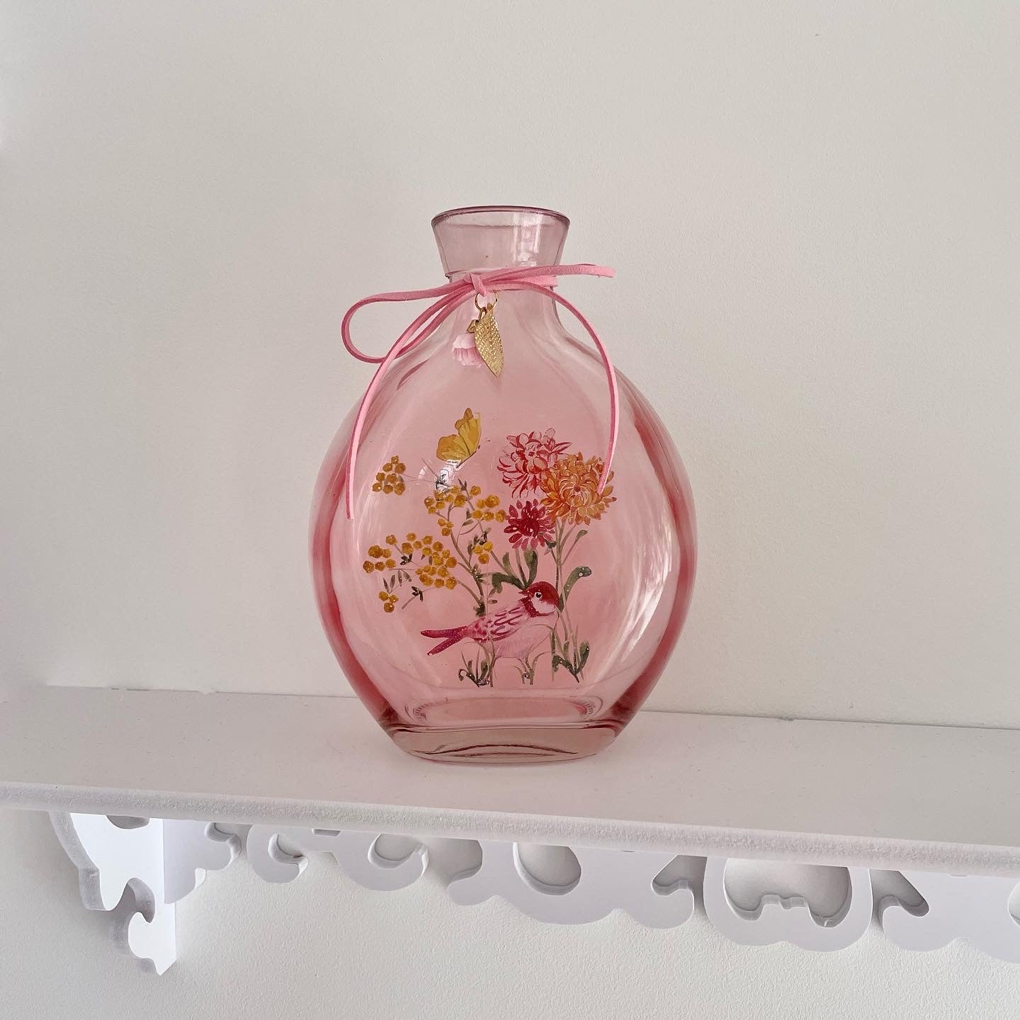 Pink floral vase made of glass and decorative with a bow and metal charms